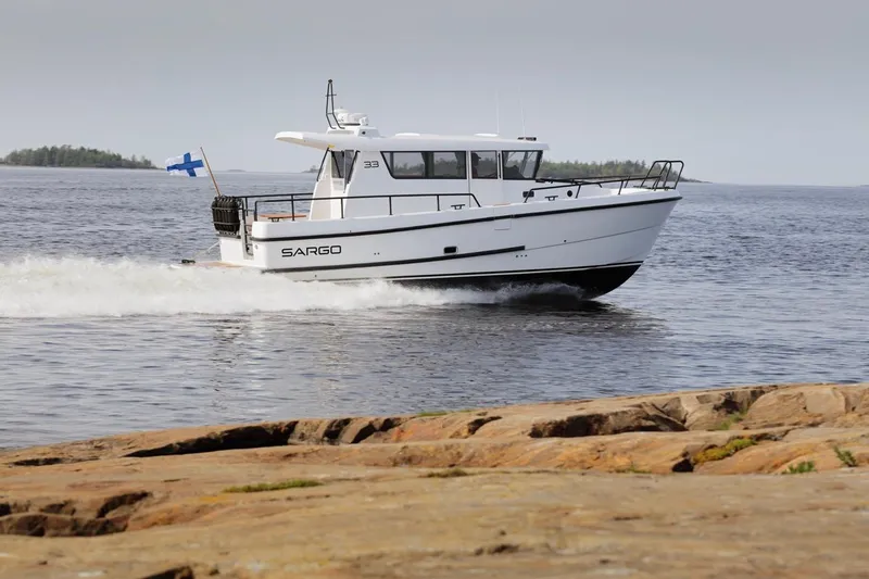 Slide: The Image of 2025 Sargo 33 boat cruising on a calm sea near rocky shore. - 6