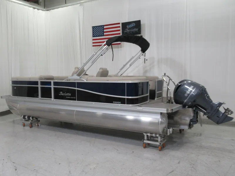 Slide: The Image of 2023 Barletta C22QC pontoon boat with outboard motor, displayed indoors. - 2