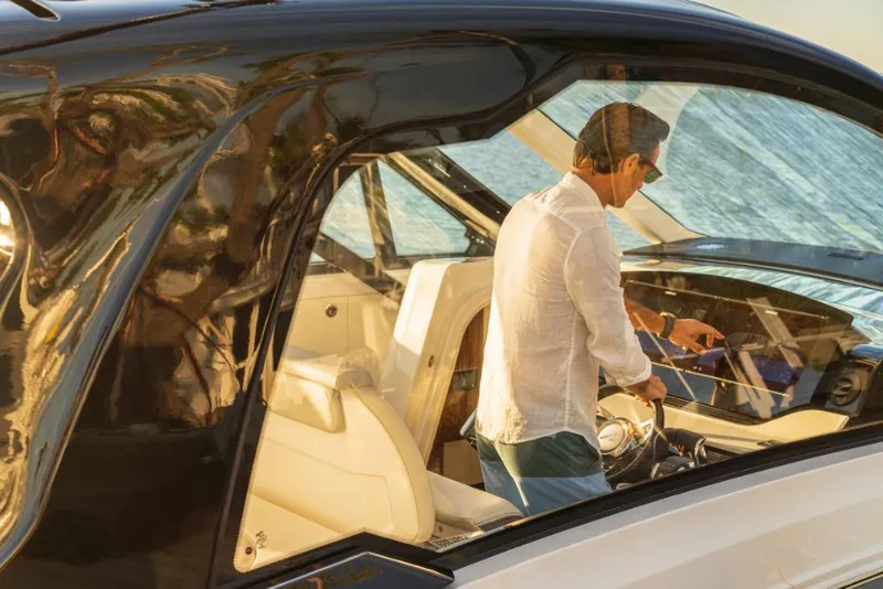 Slide: The Image of 2023 Sea Ray Sundancer 370 Outboard interior with man at helm, luxury boating experience. - 13