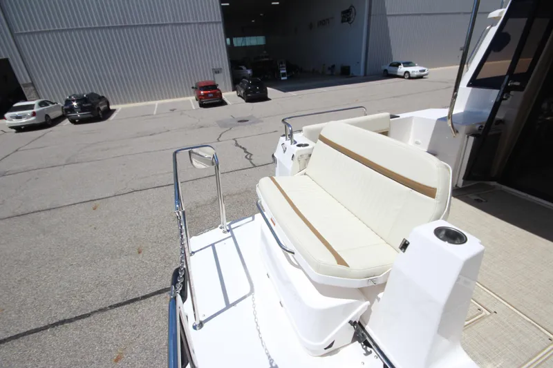 Slide: The Image of 2026 Ranger Tugs R-29 S boat with white seating, parked near a warehouse. - 10