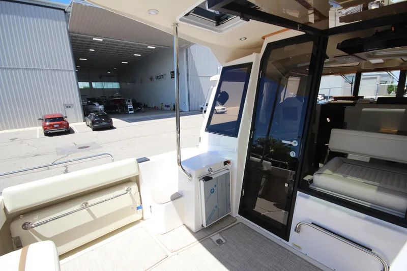 Slide: The Image of 2026 Ranger Tugs R-29 S boat interior with open door, docked near warehouse. - 15