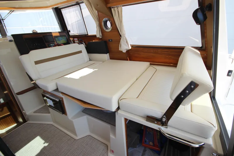Slide: The Image of 2026 Ranger Tugs R-29 S interior with convertible seating and elegant wood accents. - 22