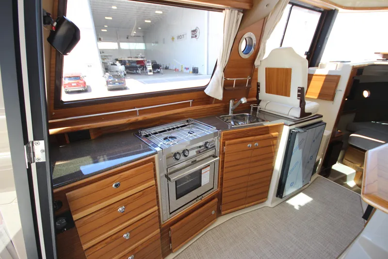 Slide: The Image of 2026 Ranger Tugs R-29 S interior kitchen with stove, sink, and wooden cabinetry. - 25