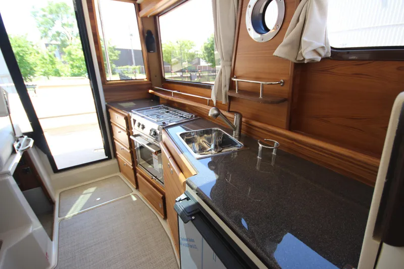 Slide: The Image of 2026 Ranger Tugs R-29 S interior kitchen with stove, sink, and wooden cabinetry. - 26