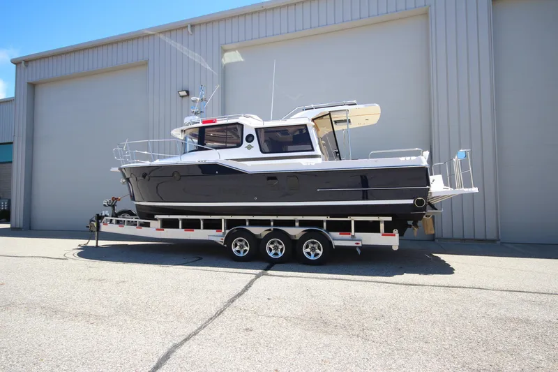 Slide: The Image of 2026 Ranger Tugs R-29 S boat on trailer, parked outside industrial building. - 3