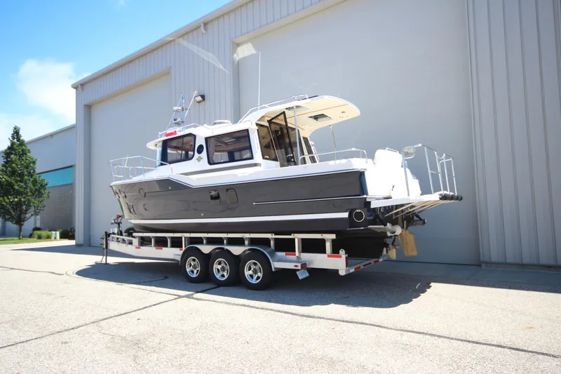 Slide: The Image of 2026 Ranger Tugs R-29 S boat on a trailer outside a large warehouse. - 4