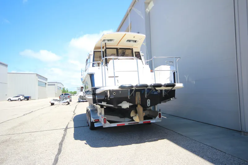 Slide: The Image of 2026 Ranger Tugs R-29 S boat on trailer, parked near industrial buildings. - 5
