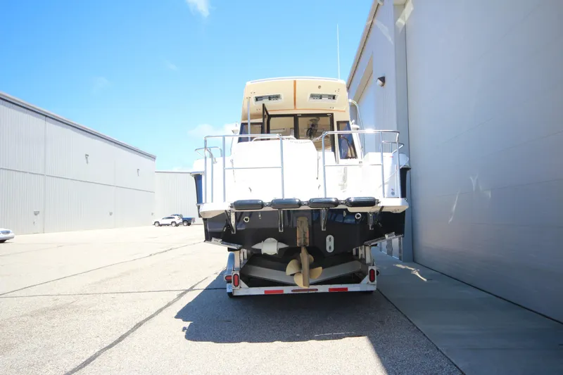Slide: The Image of 2026 Ranger Tugs R-29 S boat on trailer, parked near industrial building. - 6