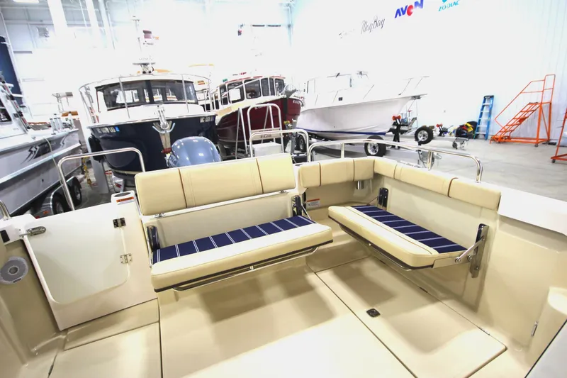 Slide: The Image of 2025 Ranger Tugs R-23 boat interior with beige and blue seating in a showroom. - 14