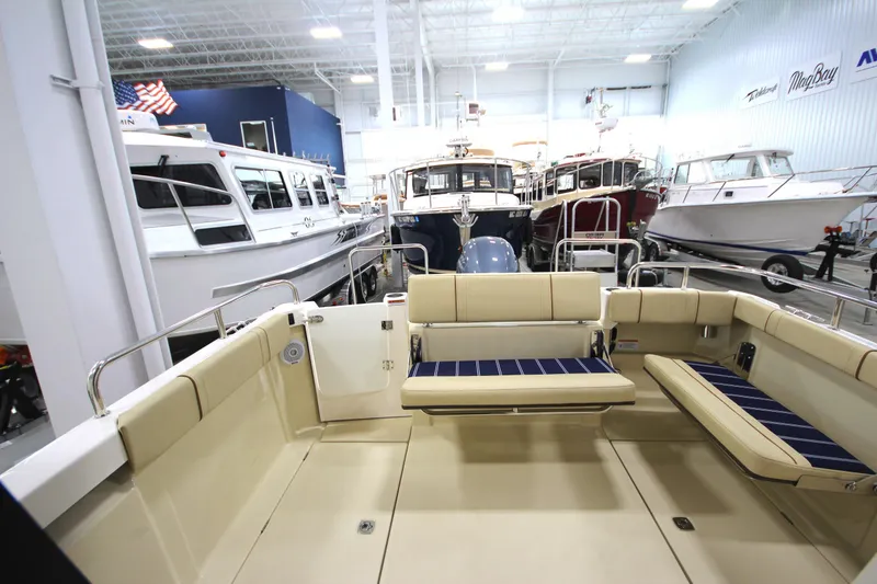 Slide: The Image of 2025 Ranger Tugs R-23 boat interior, spacious seating, and modern design in a showroom. - 15