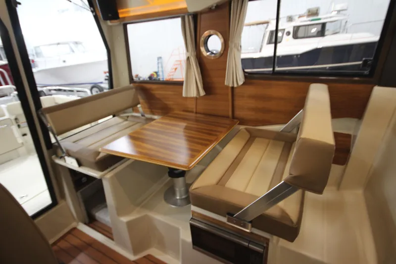 Slide: The Image of 2025 Ranger Tugs R-23 interior dining area with wooden table and cushioned seating. - 25