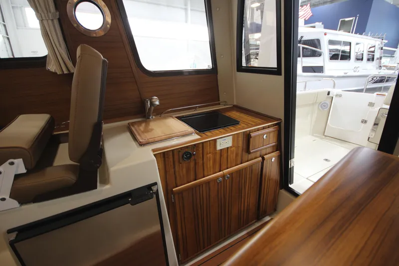 Slide: The Image of Interior of 2025 Ranger Tugs R-23 boat with wooden cabinetry and compact kitchen area. - 28