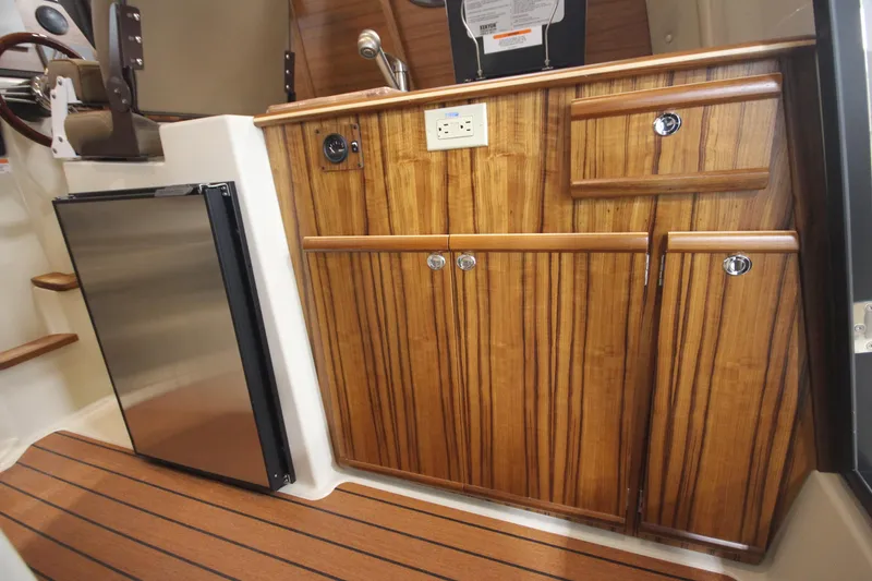 Slide: The Image of 2025 Ranger Tugs R-23 interior galley with wood cabinetry and stainless steel fridge. - 33