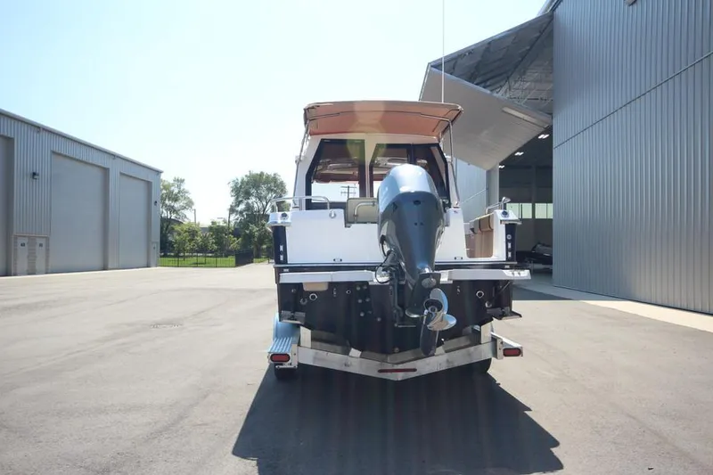 Slide: The Image of 2025 Ranger Tugs R-23 boat rear view with outboard motor in a marina. - 4