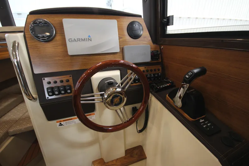 Slide: The Image of 2025 Ranger Tugs R-23 helm with Garmin navigation system and wooden steering wheel. - 45