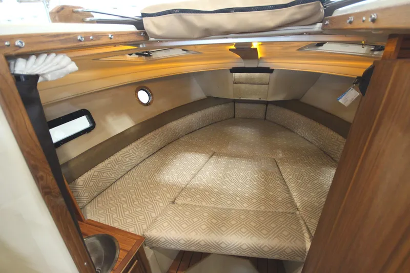 Slide: The Image of 2025 Ranger Tugs R-23 cabin interior with cushioned seating and wooden accents. - 49
