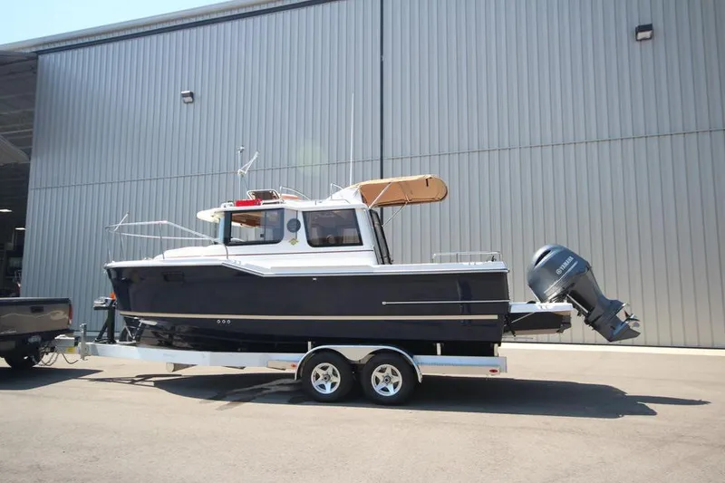 Slide: The Image of 2025 Ranger Tugs R-23 boat on a trailer outside a warehouse. - 5