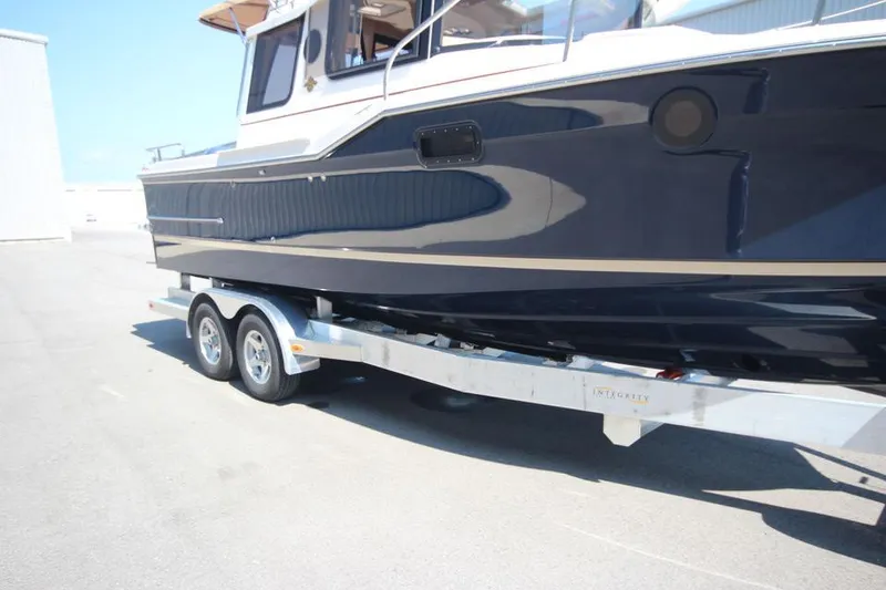 Slide: The Image of 2025 Ranger Tugs R-23 boat on a dual-axle trailer in a marina. - 8