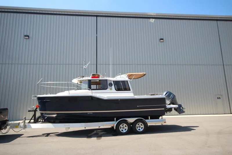 The Image of 2025 Ranger Tugs R-23 boat on a trailer in front of a large warehouse. - 0