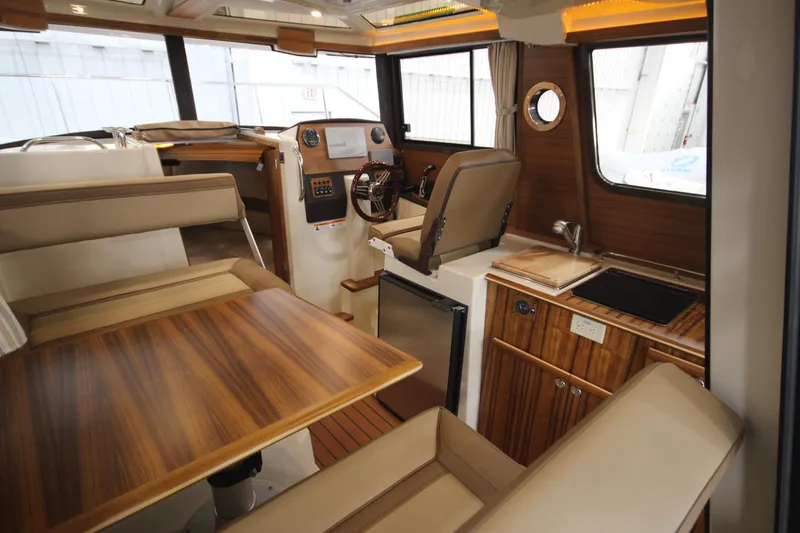Slide: The Image of 2025 Ranger Tugs R-23 interior with wood finishes, dining area, and helm station. - 24