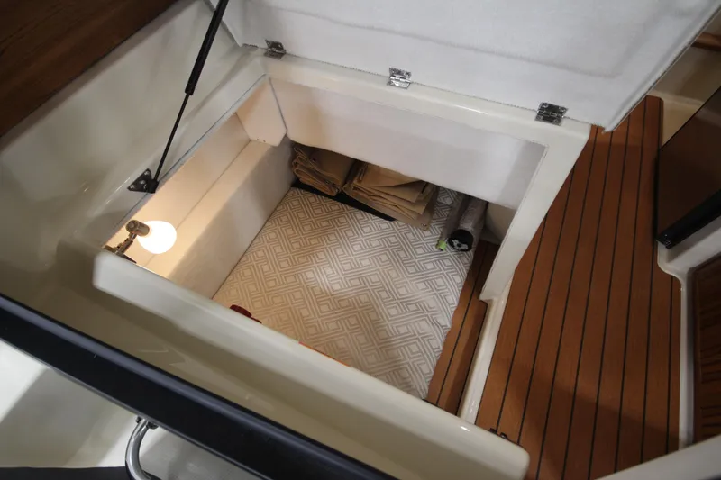 Slide: The Image of 2025 Ranger Tugs R-23 cabin storage area with wooden flooring and interior lighting. - 36