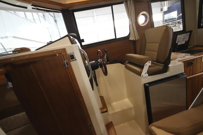 Slide: The Image of Interior helm station of 2025 Ranger Tugs R-23 boat with wooden accents and leather seating. - 43