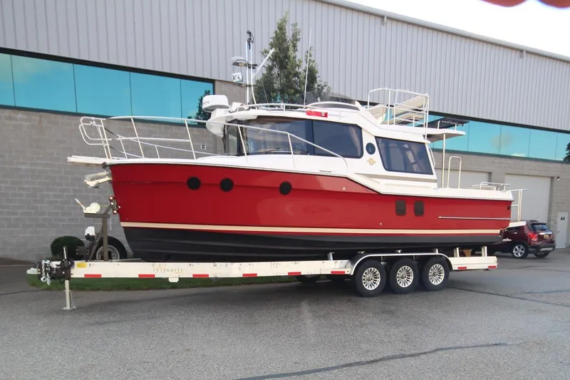 The Image of 2025 Ranger Tugs R-29 Command Bridge Luxury Edition on trailer, red and white exterior. - 0