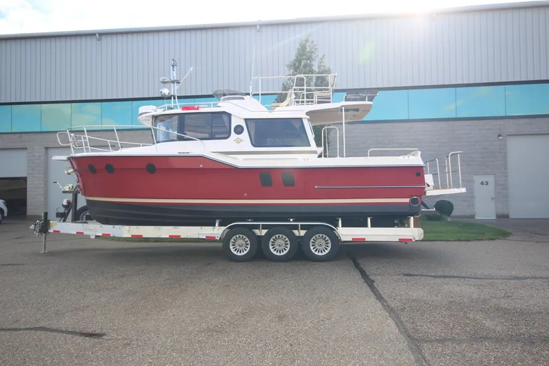 Slide: The Image of 2025 Ranger Tugs R-29 Command Bridge Luxury Edition on trailer outside warehouse. - 1