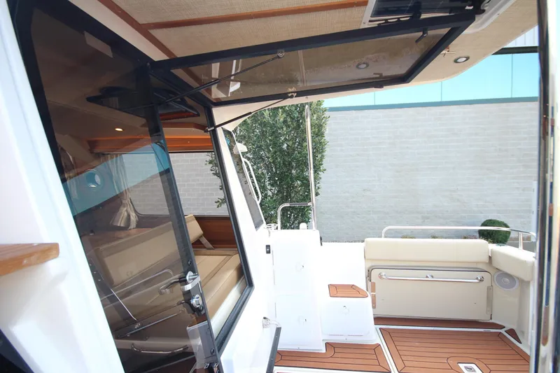Slide: The Image of 2025 Ranger Tugs R-29 Command Bridge Luxury Edition interior with open door and seating area. - 20