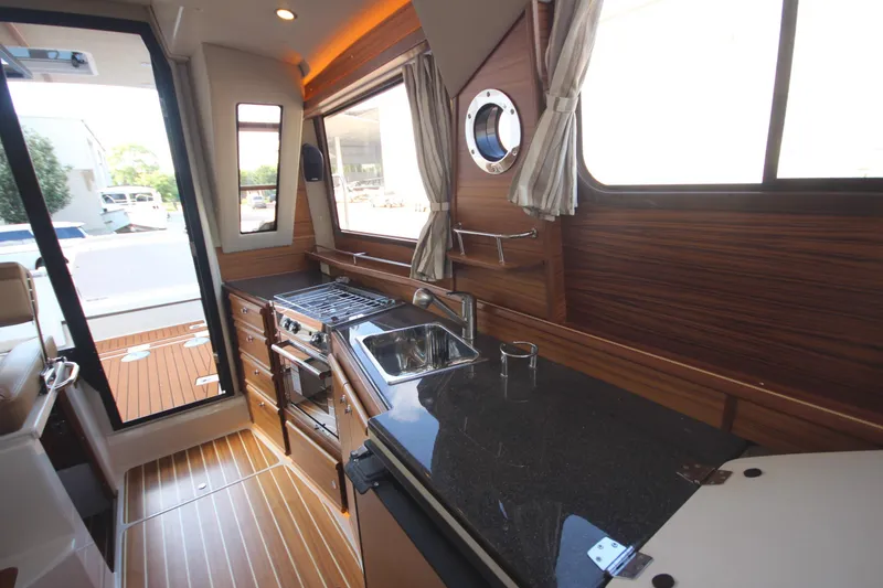 Slide: The Image of 2025 Ranger Tugs R-29 Command Bridge Luxury Edition interior kitchen with wood finish and modern appliances. - 29