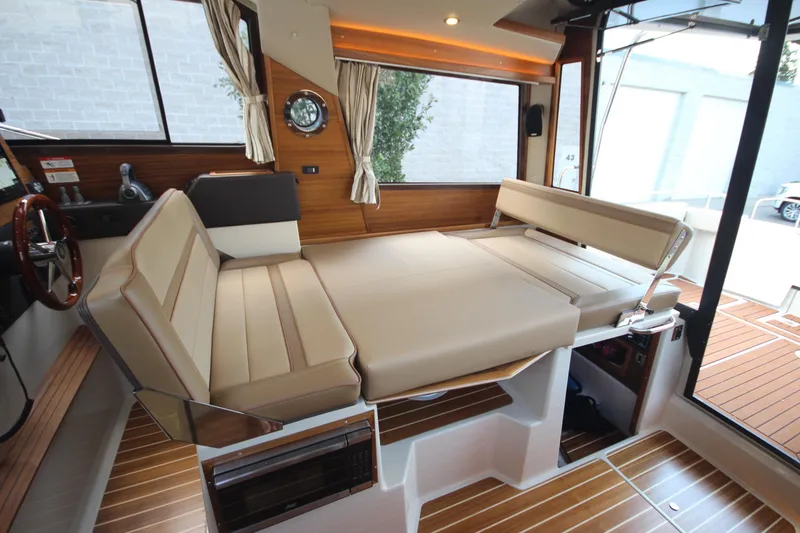 Slide: The Image of 2025 Ranger Tugs R-29 Command Bridge interior with convertible seating and wood accents. - 32