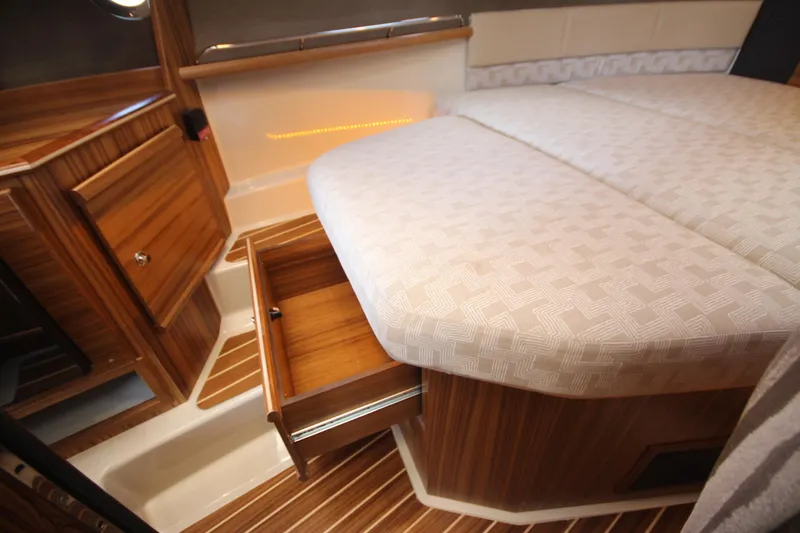 Slide: The Image of 2025 Ranger Tugs R-29 Command Bridge interior with wood cabinetry and patterned bedding. - 46