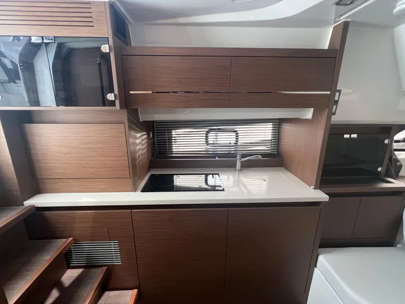 Slide: The Image of 2024 Jeanneau Leader 12.5 yacht interior kitchen with modern wood cabinetry and sleek design. - 14
