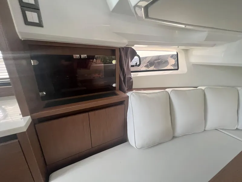 Slide: The Image of Interior of 2024 Jeanneau Leader 12.5 with white cushions and wooden cabinetry. - 17