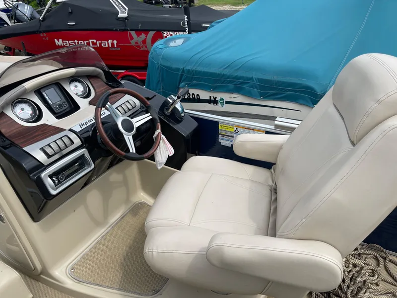 Slide: The Image of AquaPatio 240EL3 Triple 2015 boat interior with steering wheel and captain's chair. - 11