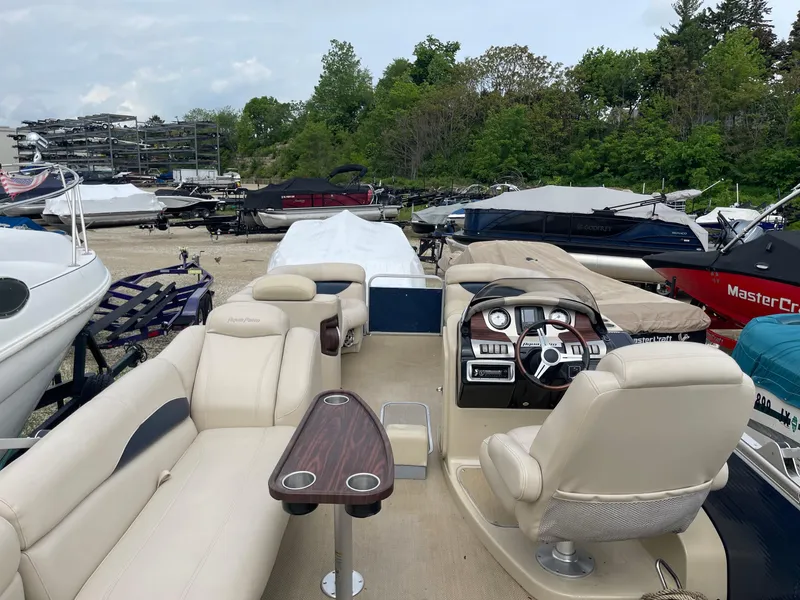 Slide: The Image of 2015 AquaPatio 240EL3 Triple pontoon boat interior with beige seating and steering console. - 3