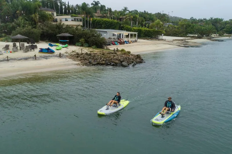 Slide: The Image of Two people kayaking on Hobie iTrek 9 Ultralight kayaks near a beach, 2023 model. - 3
