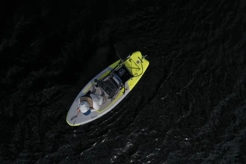 Slide: The Image of Aerial view of a person on a 2023 Hobie iTrek 9 Ultralight kayak in dark water. - 9