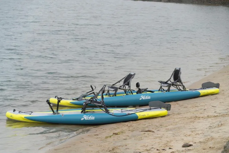 Slide: The Image of 2023 Hobie iTrek 14 Duo kayaks on sandy beach by the water. - 2