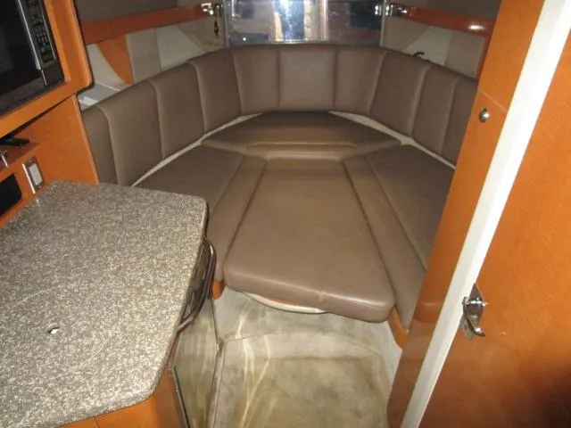 Slide: The Image of 2010 Chaparral 270 Signature cabin interior with brown seating and kitchenette. - 8