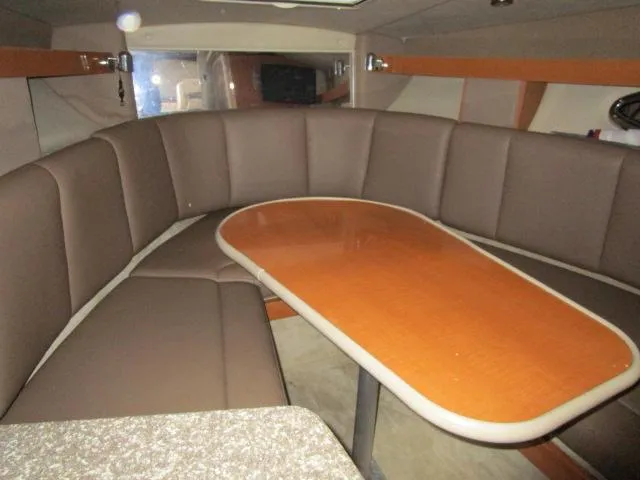 Slide: The Image of Interior of 2010 Chaparral 270 Signature boat with brown seating and wooden table. - 9