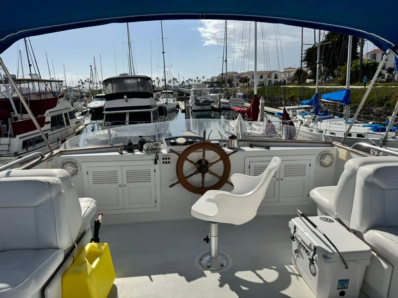 Slide: The Image of 1980 DeFever Trunk Cabin Motoryacht with Cummins repower, docked in a marina, featuring helm and seating. - 2