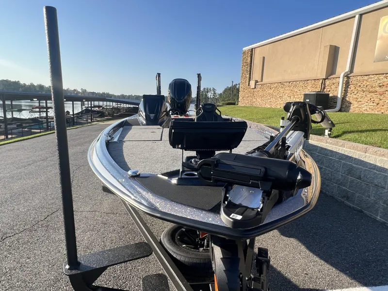 Slide: The Image of 2025 Skeeter FXR20 Limited boat on trailer, parked near a marina under clear skies. - 7