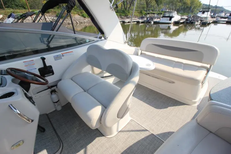 Slide: The Image of 2006 Chaparral 276 Signature Cruiser interior with plush seating and steering wheel, docked at marina. - 14