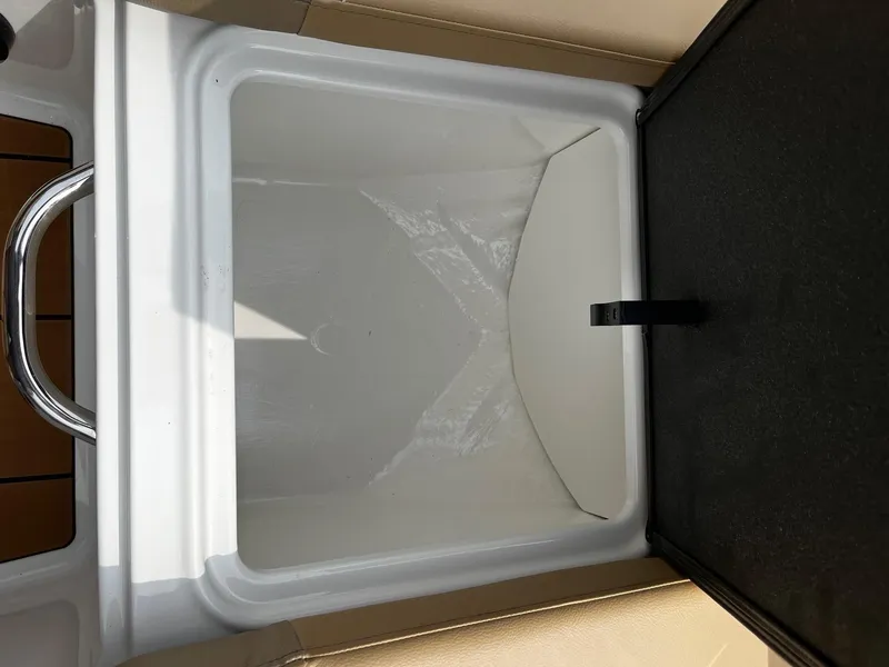 Slide: The Image of 2024 Bayliner DX2000 boat storage compartment with white interior and black lid. - 17