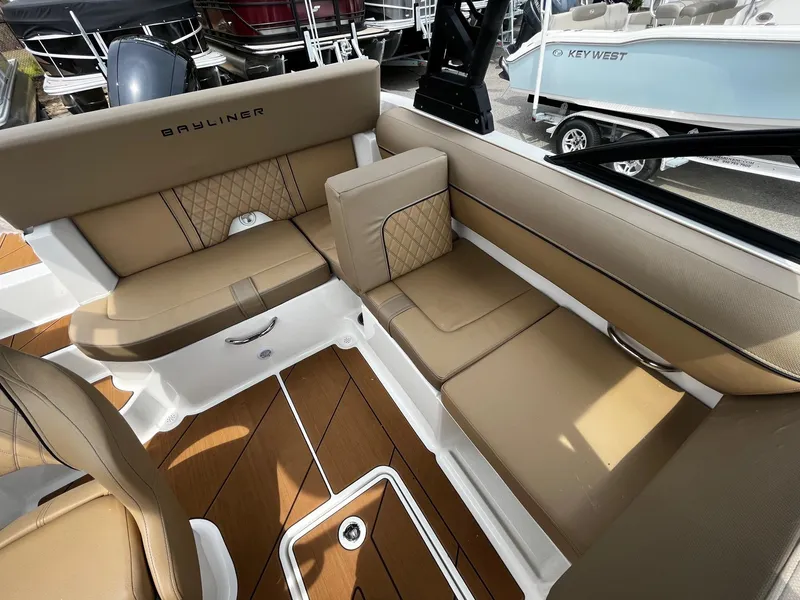 Slide: The Image of 2024 Bayliner DX2000 boat interior with tan seating and wood flooring. - 12