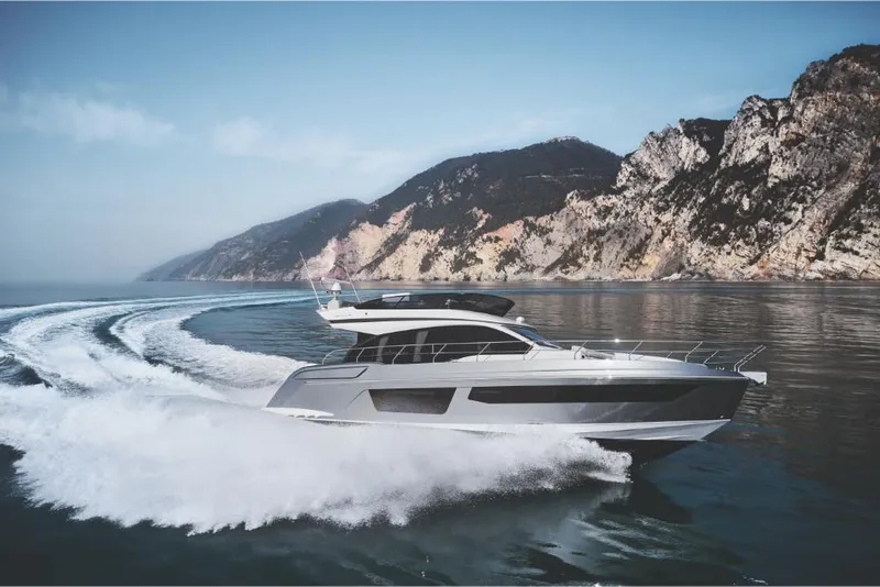 Slide: The Image of 2023 Azimut 53 yacht cruising near scenic coastal cliffs. - 2