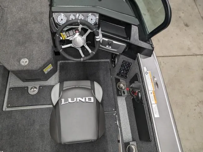 Slide: The Image of 2025 Lund 1975 Pro V Sport boat interior with steering wheel and branded seat. - 13