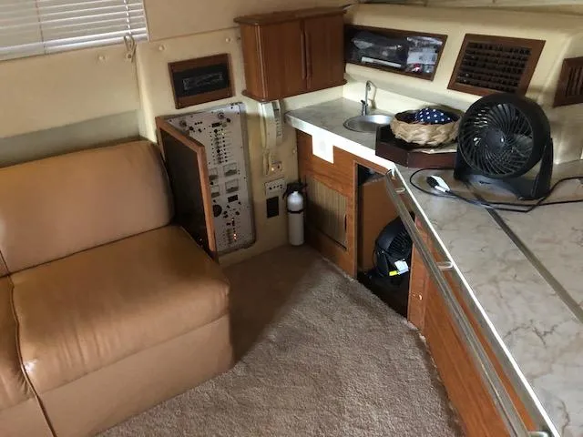 Slide: The Image of Interior of 1983 Sea Ray 390 Sport Fisherman with beige seating and compact kitchen area. - 20