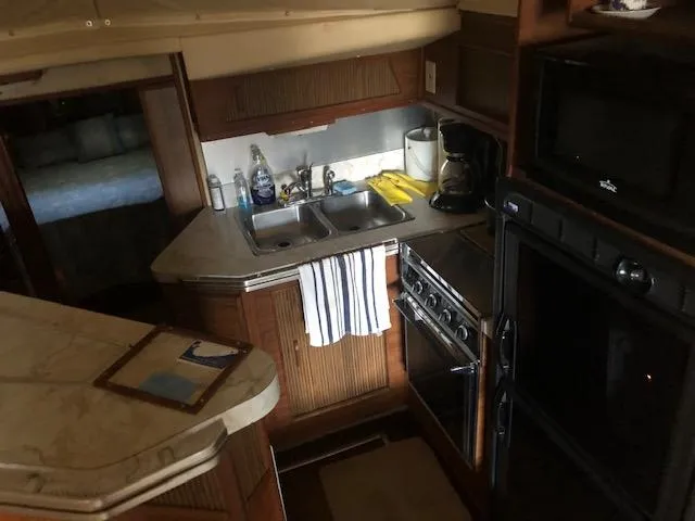 Slide: The Image of 1983 Sea Ray 390 Sport Fisherman kitchen with sink, stove, and microwave. - 22